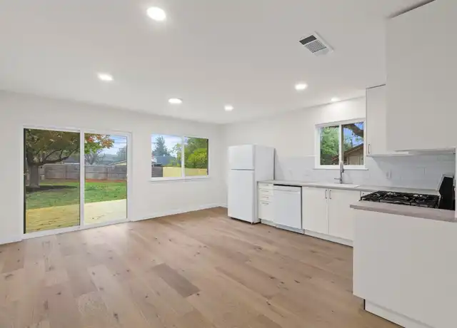 Kitchen with custom backsplash and light hardwood in Travis County home